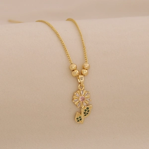 Detailed close-up of a 18K gold sunflower pendant with pink, white, and green gems