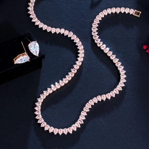 Detailed close-up of rose gold zircon necklace and earrings set on black background