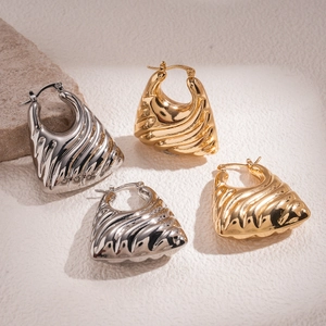 Detailed view of gold and silver textured geometric hoop earrings on a stone background