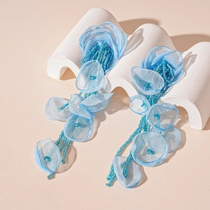 Close-up of blue handmade lace flower earrings with delicate beaded tassels and petals