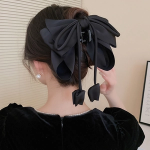 Détail d'une pince à cheveux élégante avec nœud noir et pompons sur une coiffure française