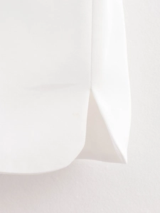 Detailed macro view of small side split design and woven texture on white vest hem