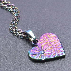 Vue macro d'un pendentif coeur arc-en-ciel plaqué 18k avec gaufrage marguerite sur noir