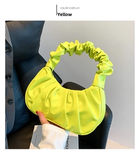 Detail of trendy yellow ruched crescent handbag with elastic handle on soft PU leather