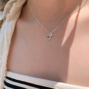 Minimalist 925 sterling silver necklace with light blue crystal pendant on a female model