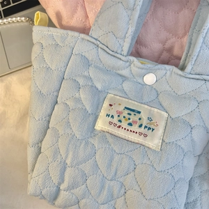 Macro detail of heart-quilted texture and cute happy patch on light blue tote bag