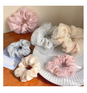 Dettaglio di elastici scrunchie in organza floreale in rosa, blu e beige