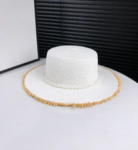 Close-up of white straw sun hat featuring elegant pearl trim and fringe brim details