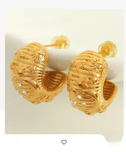 Detailed close-up of C-shaped 18k gold earrings with celestial star and moon carvings