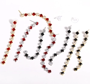 Detail of star-shaped crystal drop earrings with zirconia in red, black, and white colors