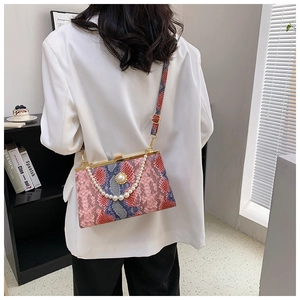 Sac à main chic aspect serpent avec chaîne de perles porté par un mannequin en blazer