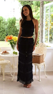 Detail of a black sleeveless halter neck top and layered maxi skirt on a sunny terrace
