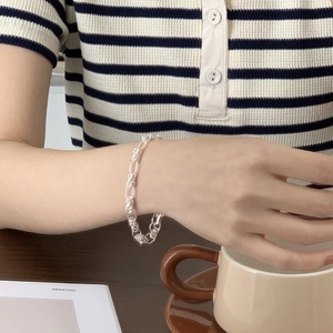 Detailed close-up of a 925 sterling silver woven link bracelet on a woman's wrist