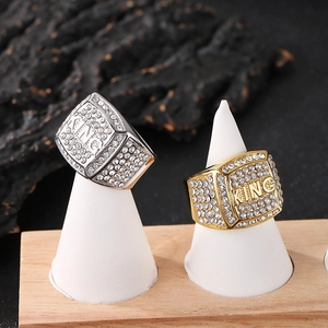 Macro detail of iced-out gold KING ring with square CZ stones on a white jewelry stand