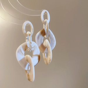 Detailed texture of geometric acrylic chain earrings with amber marble pattern and link design