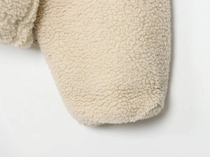 Detail view of the thick sherpa fleece cuffs on a loose-fit cream half-zip sweatshirt