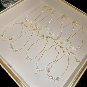 Detailed view of adjustable gold-plated bracelets with cubic zirconia charms on a jewelry tray