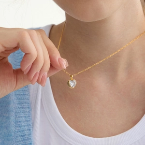 Primo piano di una collana con ciondolo a cuore in zircone placcato oro 18k su una modella