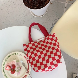 Detail of red and white checkered corduroy lunch bag with snap button on white table