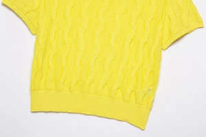 Vista detallada del top de punto amarillo con manga corta y textura de trenzas onduladas