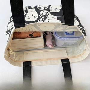 Interior view showing large capacity and inner pockets of the off-white canvas tote bag