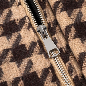 Detailed close-up of metal zipper and brown houndstooth wool fabric on a vintage jacket