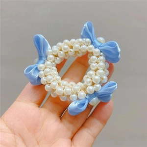 Hand holding a cute pearl hair tie for girls featuring a blue ribbon bow detail