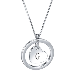 Detail of silver round pendant with heart cutout and engraved letter G on chain