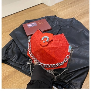 Detail showing red diamond-shaped quilted crossbody bag with silver chain on black leather jacket