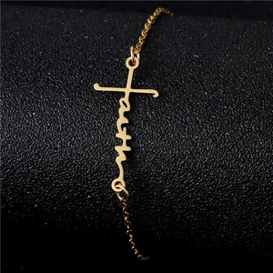 Polished gold faith cross bracelet with intricate letter design on a black background