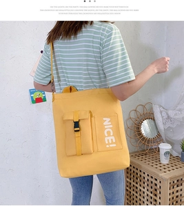 Detail of yellow canvas tote bag with adjustable strap and white NICE lettering