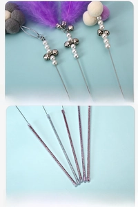 Detail of cat wand featuring purple feathers, pearls, and bells with a glitter acrylic stick