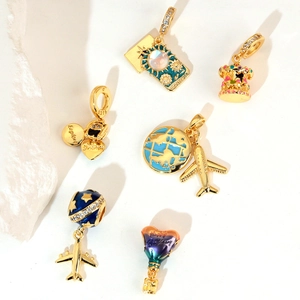 Gold travel charms collection featuring zircon aircraft, globe, and camera on white stone
