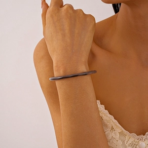 Gros plan d'un bracelet fin en résine marron foncé sur le poignet d'un mannequin