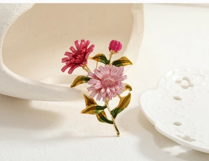 Macro detail of a hand-painted pink daisy brooch with gold trim leaning on a ceramic vase