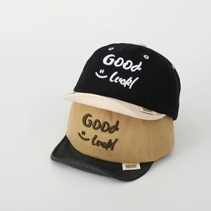 Detail of embroidered Good Luck text and smiley face on soft brim cotton baby caps