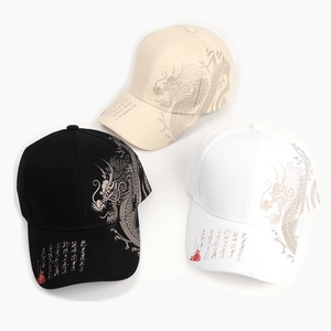 Detailed view of baseball caps in black, white, and beige with dragon and calligraphy design