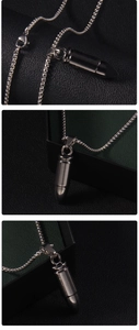 Polished dark metal bullet pendant with silver box chain displayed on textured leather