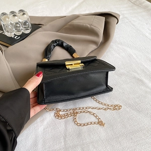 Primer plano de bolso acolchado negro con asa fruncida y correa de cadena dorada