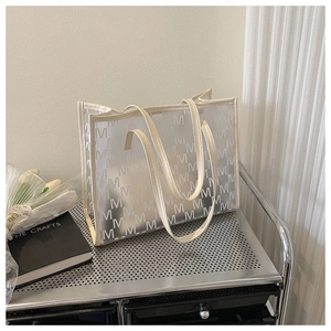 Close-up of a large transparent tote bag with M letter prints on a silver metal cart