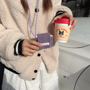 Mini purple plush earphone pouch with crossbody strap shown in outdoor lifestyle scene
