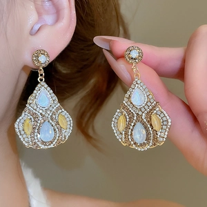 Macro shot of elegant teardrop opal earrings with micro-inlaid crystals and gold finish