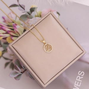 Detail of 18K gold zodiac pendant featuring an archer design with micro-paved crystals