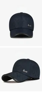 Detail of navy quilted winter baseball cap featuring ear protection and metal badge