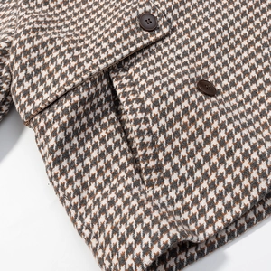 Detail eines Wollmantels mit Hahnentrittmuster, braunen Knöpfen und Tweed-Struktur