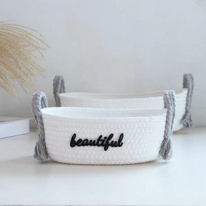 Detail of woven cotton rope baskets with gray tassel handles and beautiful embroidery