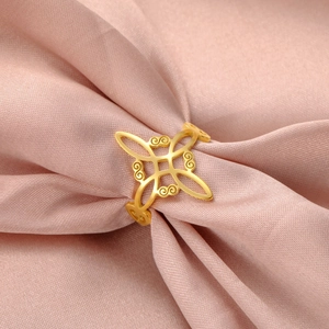 Close-up of golden stainless steel Witch's Knot ring on elegant pink silk background