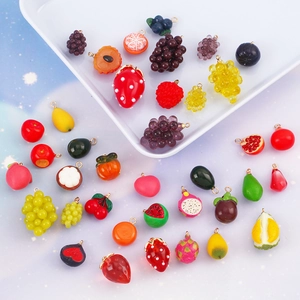 Colorful resin fruit charms like strawberry and grape with metal rings on blue background