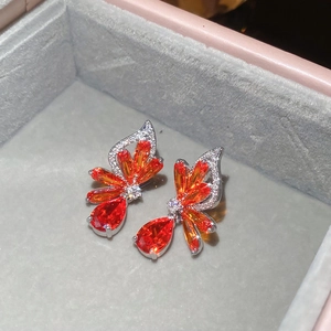 Detailed macro view of silver zircon butterfly wing earrings with vibrant orange stones