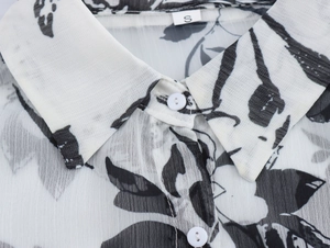 Detail of the shirt collar with black and white floral print and white round buttons
